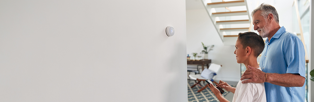 Man and boy controlling thermostat from phone 