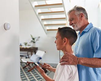Man and boy controlling thermostat from phone 